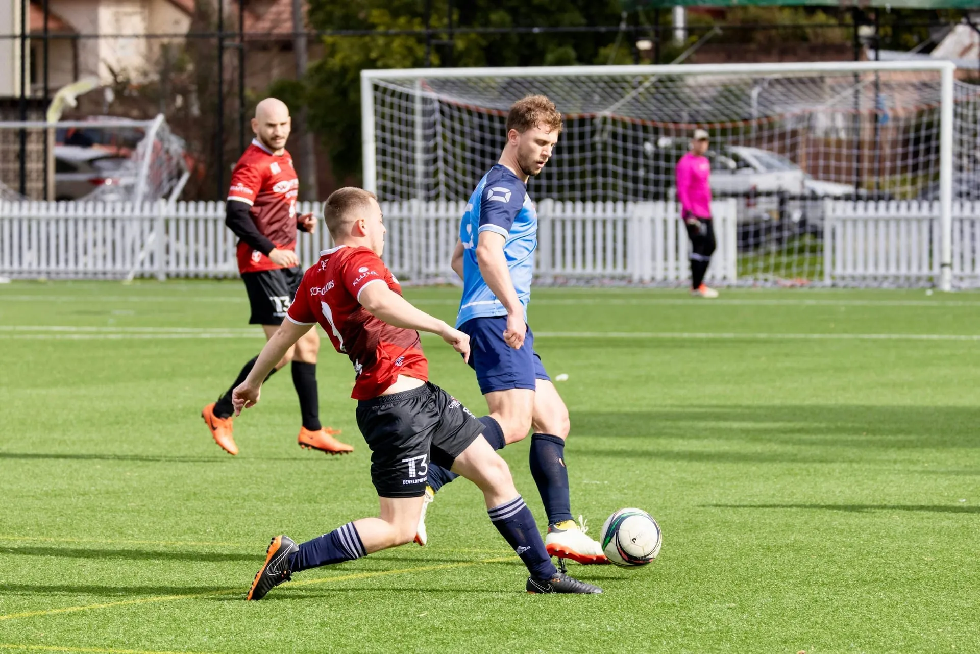 Two soccer players contest a midfield duel on synthetic turf at a Northern BC pitch